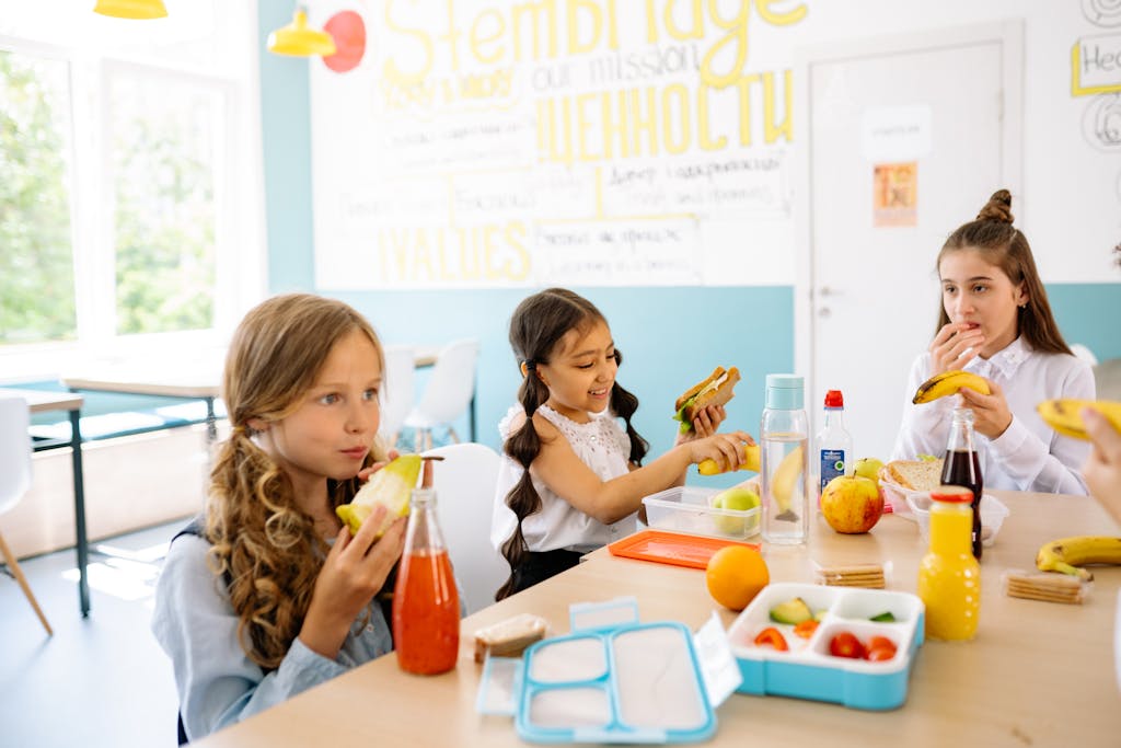 Group of schoolgirls having a break, eating healthy snacks at a canteen table.